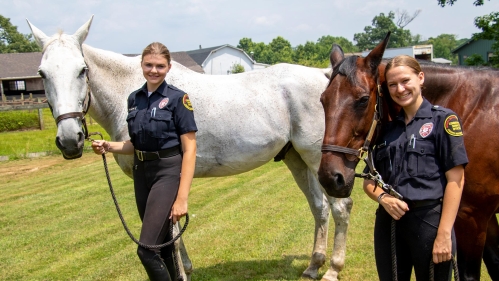 Two Mounted Patrol students standing with their horses.