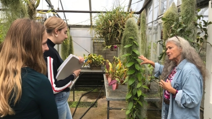 A professor and two students in a greenhouse.